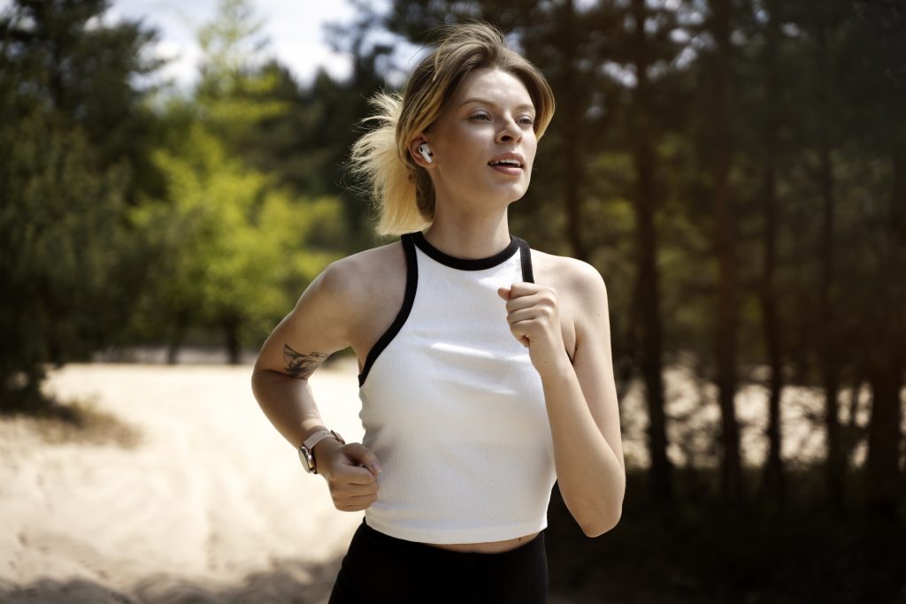 Woman jogging outdoors wearing Apple AirPods Pro, showcasing their portability and secure fit during workouts.