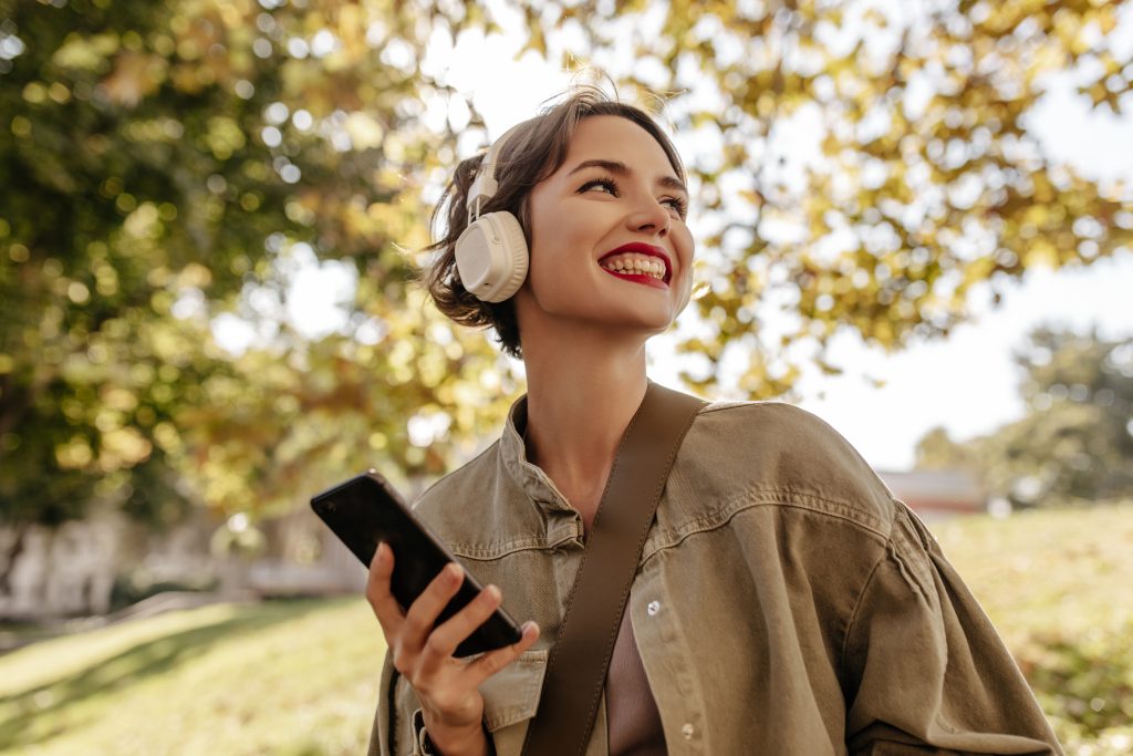 Girl walking in a park wearing Sony WH-1000XM4 headphones, showcasing their sleek, wireless design and comfort.